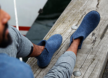 A close up picture of a person's feet wearing glerups boots in the color Denim blue with black rubber soles. 