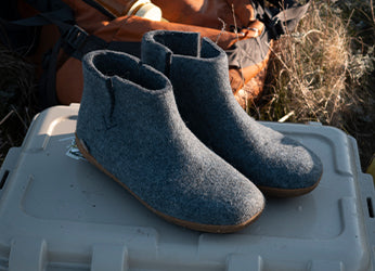 A close up picture of glerups boots in the color Denim blue with natural rubber soles placed outdoors. 