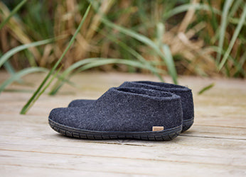 Close up picture of glerups shoes in the color Charcoal grey with black rubber soles placed outdoors on the terrace. 